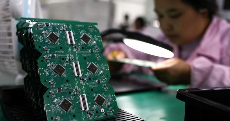 An employee inspects a printed circuit board at a factory, in Dongguan