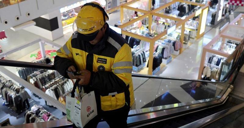 FILE PHOTO: Delivery worker picks up a food order at a shopping mall in Beijing