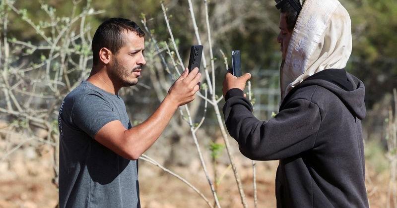 Yousef Hassan whose house was been encircled by militant settlers and later taken over by the military, films an Israeli settler