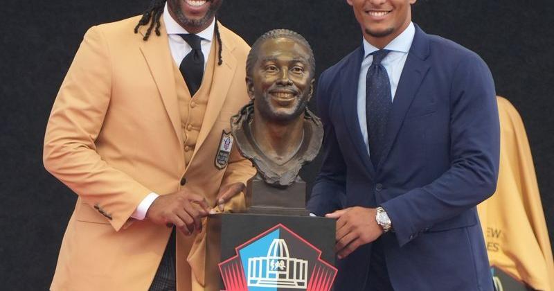 Pro Football Hall of Fame enshrinee Larry Fitzgerald and his son Devin Fitzgerald pose with his bust during the Class of 2026