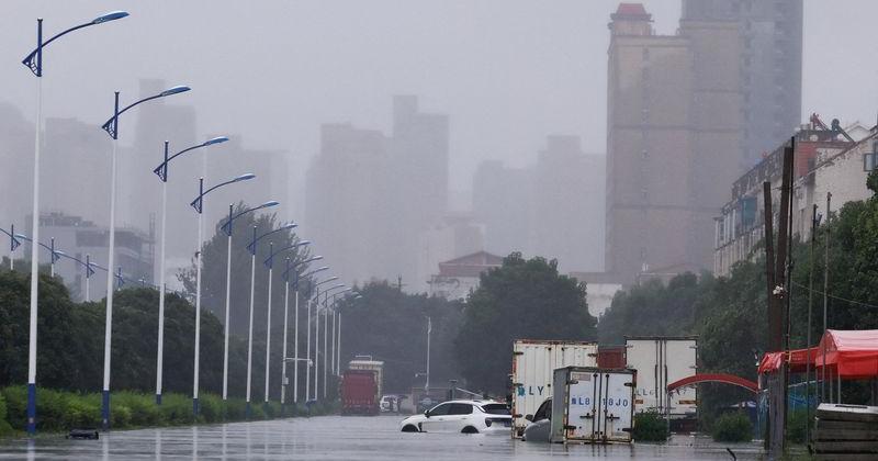 Vehicles are partially submerged in floodwaters on a street, amid heavy rainfall brought by remnants of Typhoon Dolphin, in Luohe