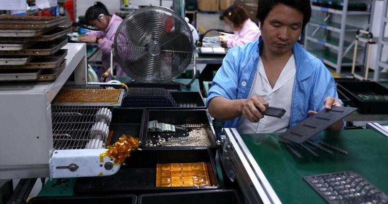 FILE PHOTO: An employee works on an assembly line for printed circuit boards at a factory, in Dongguan