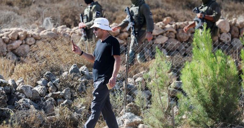 Loui Ridi, a Palestinian-American whose house has been besieged by settlers for over a week, films his property as Israeli soldiers walk on the road behind him