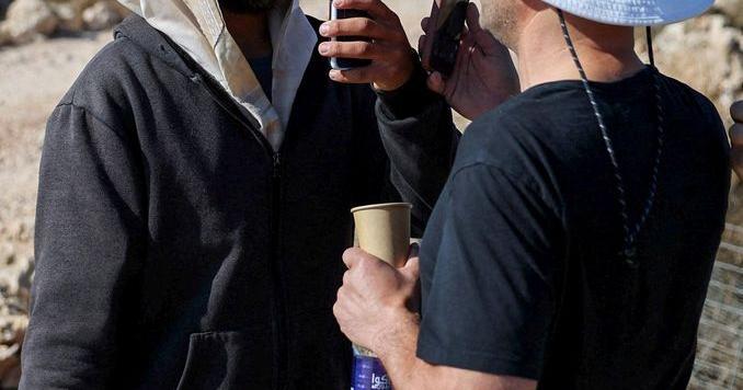 Palestinian-American Loui Ridi (R), whose house was encircled by militant settlers for over a week, films an Israeli settler (L) who entered his property in Qusra