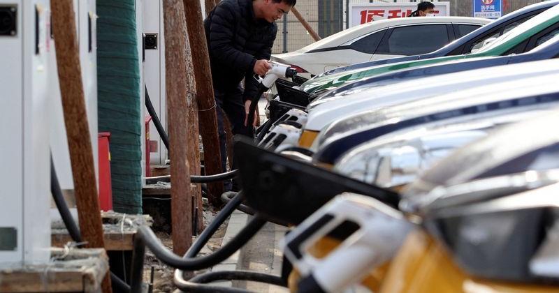 A man charges a car at an EV charging station in Beijing