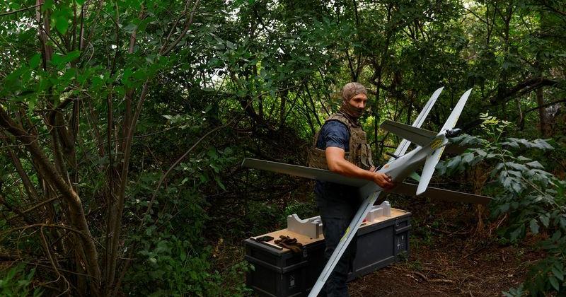 Ukrainian service member carries a RAM-2X strike drone to a launch point, at a position near a front line in Southern Ukraine