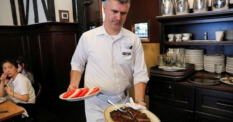 A waiter serves steak at Peter Luger Steak House in Brooklyn, New York City