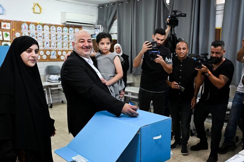 Palestinian candidate Mansour Abbas, leader of the Ra'am party, holds his  daughter as he places his vote at a polling station, on the day of Israel's  national election, in Maghar | Top