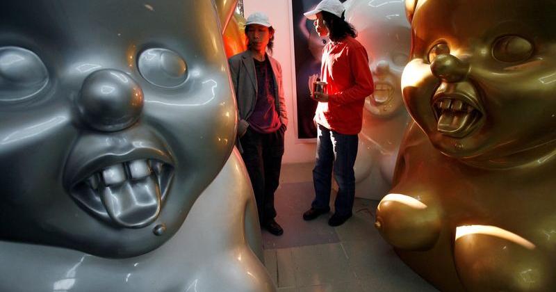 FILE PHOTO: Chinese artists the Gao Brothers walk past some of their 