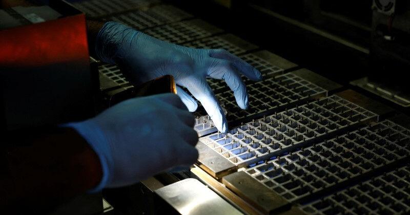 A technician checks the machine with a flashlight at a solar panel manufacturing hub, in Greater Noida