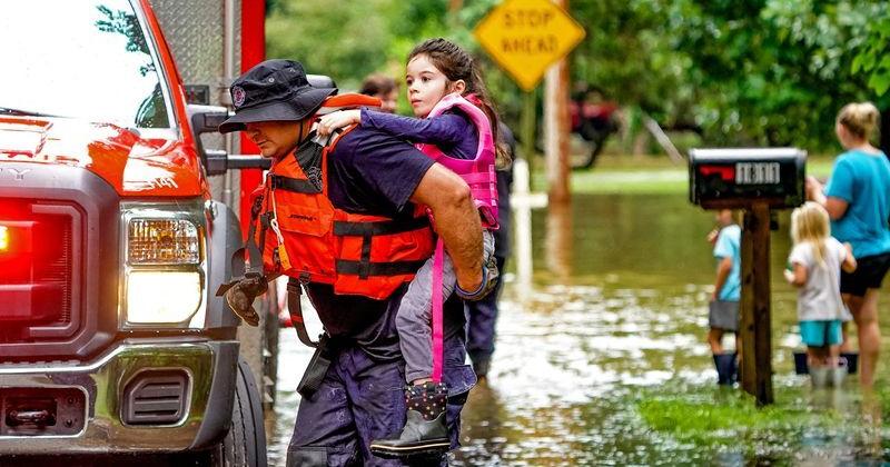 A girl is carried from flood waters as evacuations are underway in the Ravenswood neighborhood due to flooding after days of heavy rain in Indianapolis, Indiana, on Aug. 15, 2026.