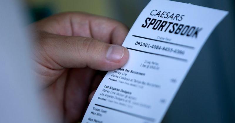 A man looks at his ticket after placing a bet at the Caesars Sportsbook betting window at Chase Field in Phoenix on the first day of sports betting on September 9, 2021. Chase Field is the first major league stadium to have sports betting.
