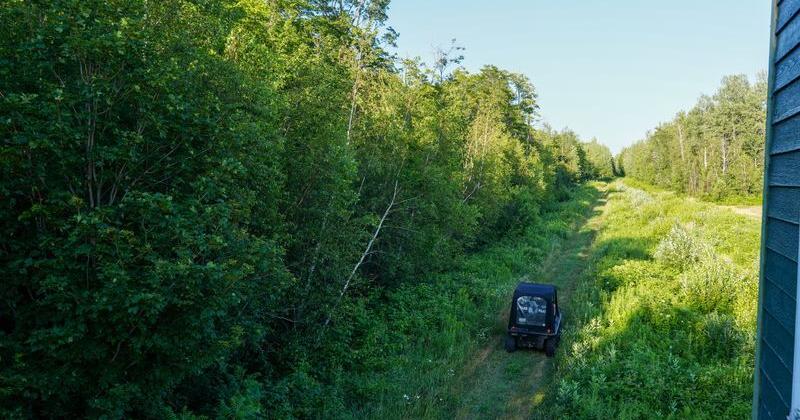 Sgt. Jonathan Maheu of the Royal Canadian Mounted Police drives an eight-wheel ATV along the international boundary between the United States and Canada near the New York State border on July 15, 2026. The 20-foot-wide “slash” through the trees and brush runs for more than 1,000 miles, a significant portion of the approximately 5,000-mile-long border between the two countries.