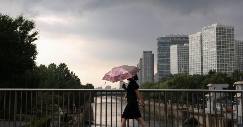 Woman holds an umbrella as she walks amid rainfall under the impact of Typhoon Dolphin in Beijing