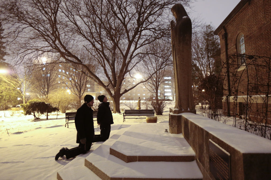 Seminarians praying before statue