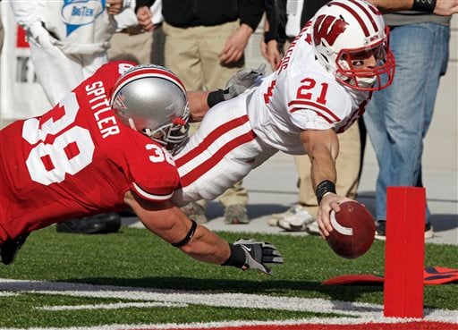 (2009) Wisconsin Cornerback Chris Maragos (21), the Badgers holder on kicks, dives in for a touchdown under Ohio State linebacker Austin Spitler (38) on a fake field-goal attempt in the second quarter.  Photo Via: Terry Gilliam/Associated Press