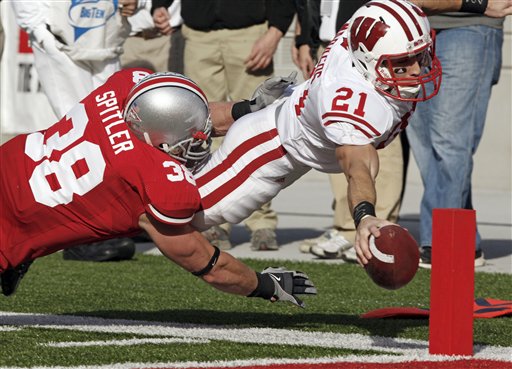 (2009) Wisconsin Cornerback Chris Maragos (21), the Badgers holder on kicks, dives in for a touchdown under Ohio State linebacker Austin Spitler (38) on a fake field-goal attempt in the second quarter. Photo Via: Terry Gilliam/Associated Press