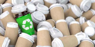 Recycling sign on one of the heap of many empty paper coffee cups.