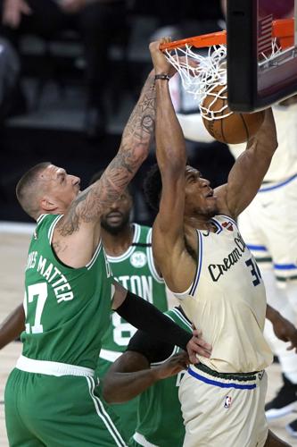 Orlando Magic's Nikola Vucevic (9) drives past Boston Celtics' Daniel Theis  (27) and Semi Ojeleye (37)