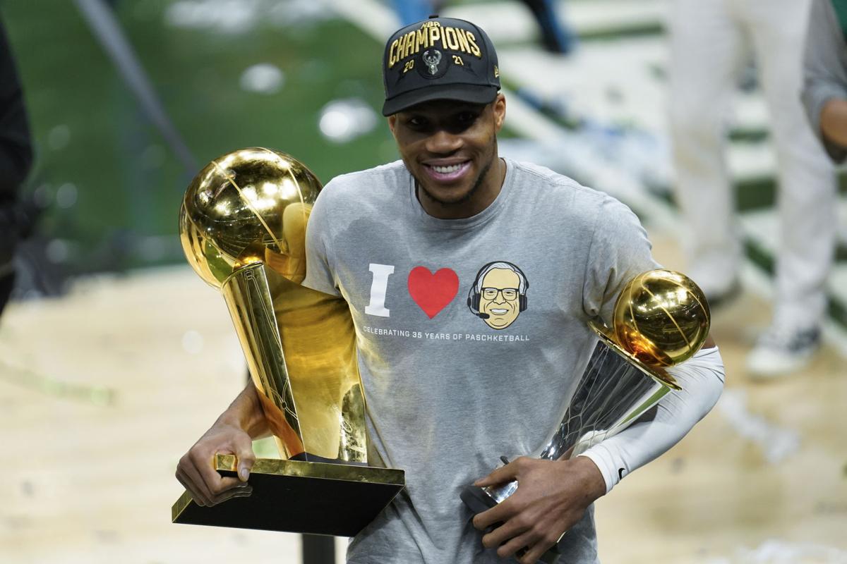 Milwaukee Bucks' Giannis Antetokounmpo holds up the NBA Championship trophy  and Finals MVP trophy to the crowd during a parade celebrating the  Milwaukee Bucks' NBA Championship basketball team Thursday, July 22, 2021