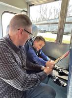Head Start bus driver helps a young passenger