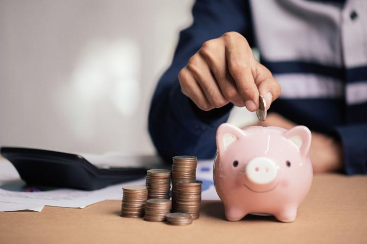 Man hand putting money coin into piggy for saving money wealth and financial concept.
