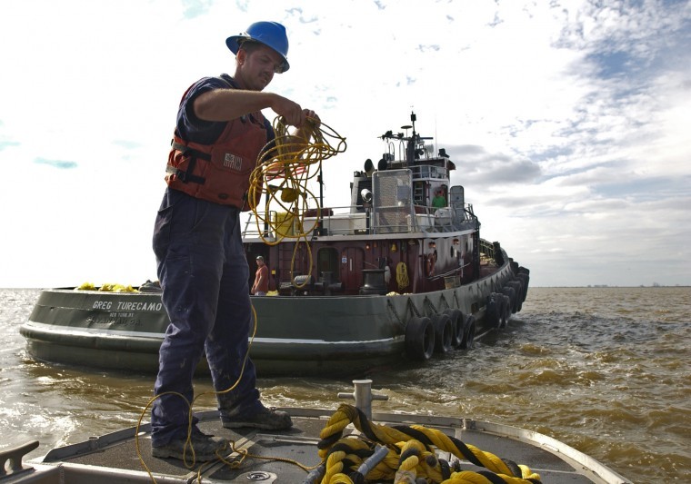 A member of the U.S. Coast Guard pulls in a tugboat