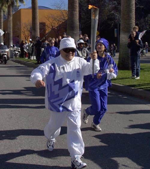 Torchbearer Yosh Uchida carries the Olympic Flame during the 2002 Salt Lake Olympic Torch Relay in San Jose, California.