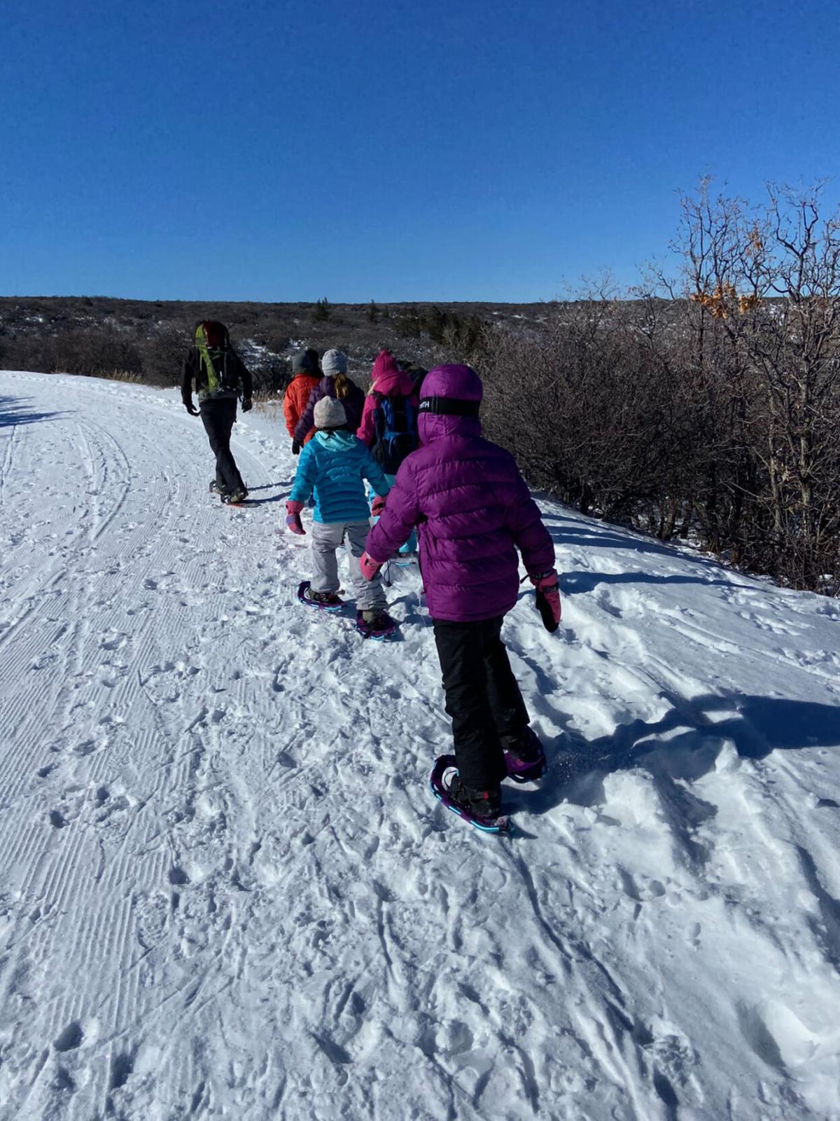 2 kids snowshoeing on groomed trail