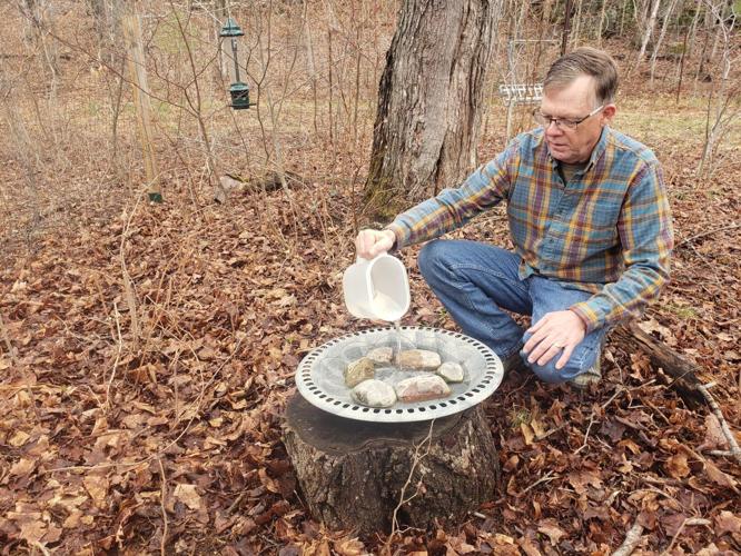 Rick Stronks pours water into a large bowl lined with rocks