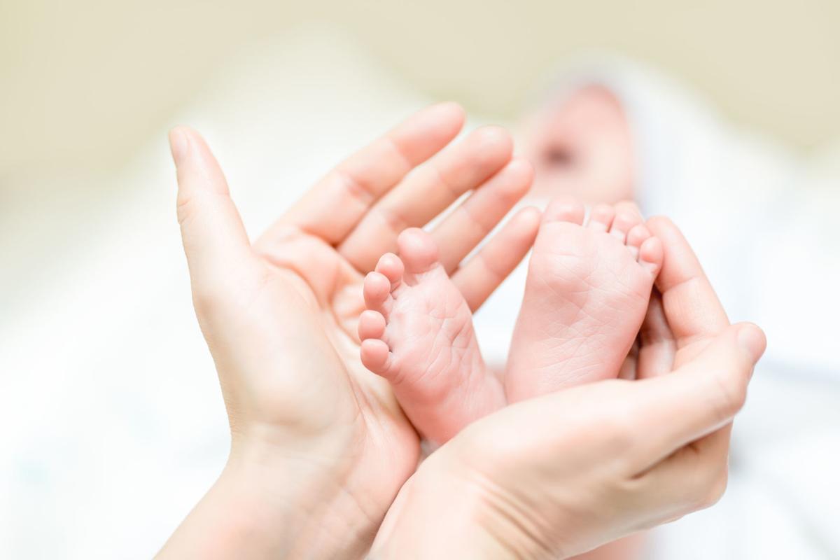Mother holding feet of newborn baby.