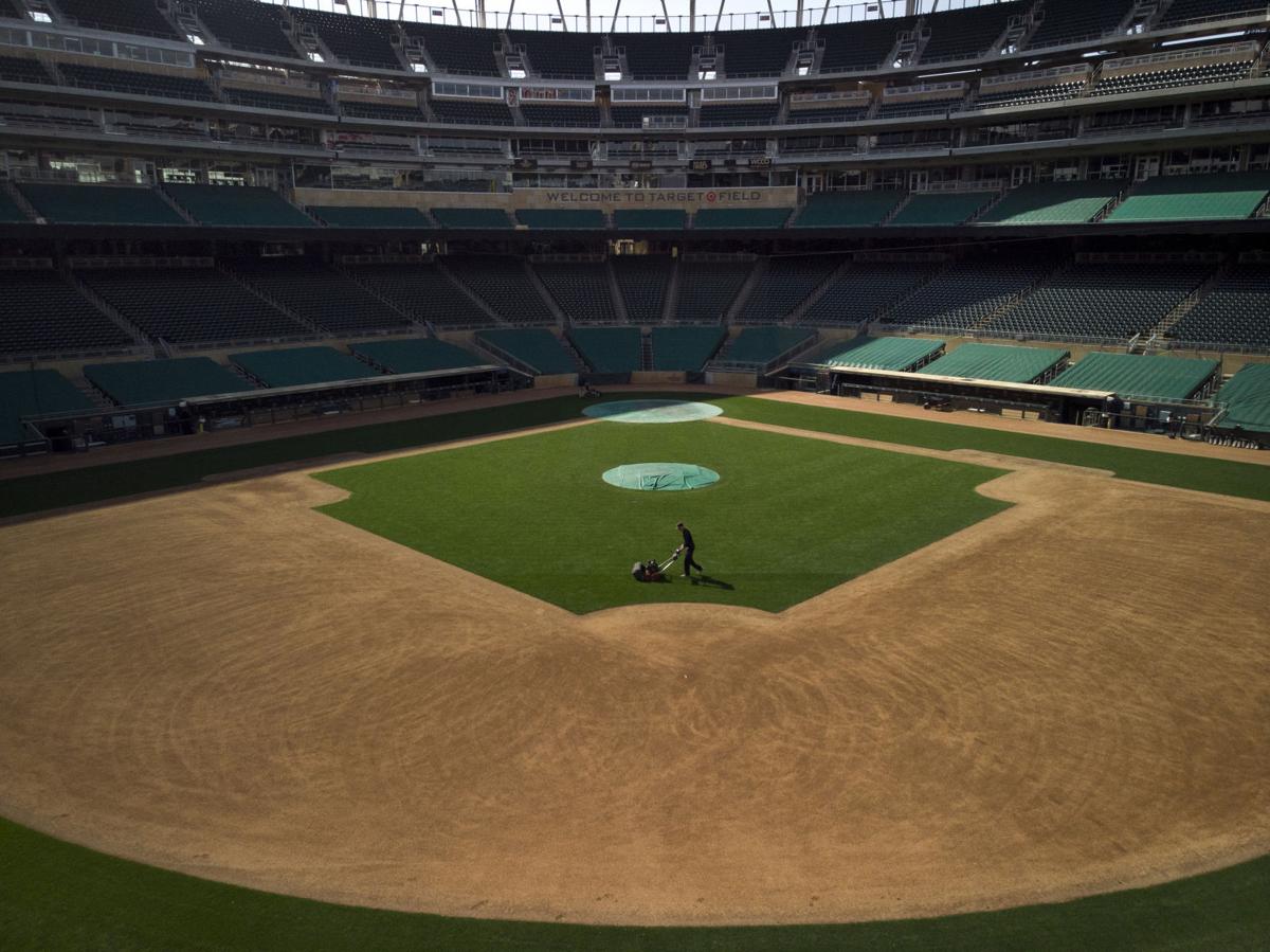 A skeleton crew of grounds keepers cut the grass at Target Field Friday afternoon, March 27, 2020 in Minneapolis, Minn.