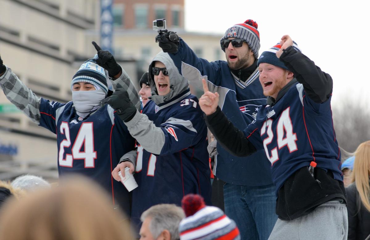 Patriots fans in front of the Boston Public Library cheer as the tail end of the team's celebratory parade passes.