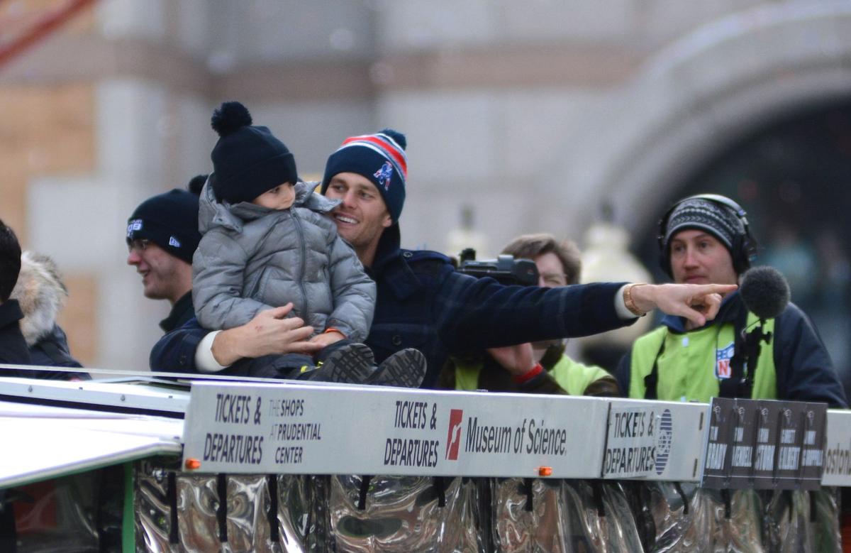 Patriots Quarterback Tom Brady holds his son on top of one of the Duck Boats heading down Boylston Street during the team's celebratory parade.
