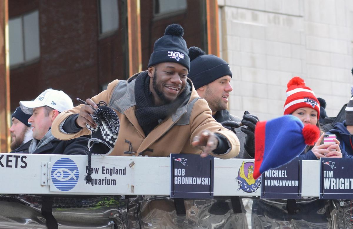 Patriots Tight End Tim Wright tosses a hat back to the crowd after autographing it for a fan that tossed it to him during the team's celebratory parade down Boylston Street.