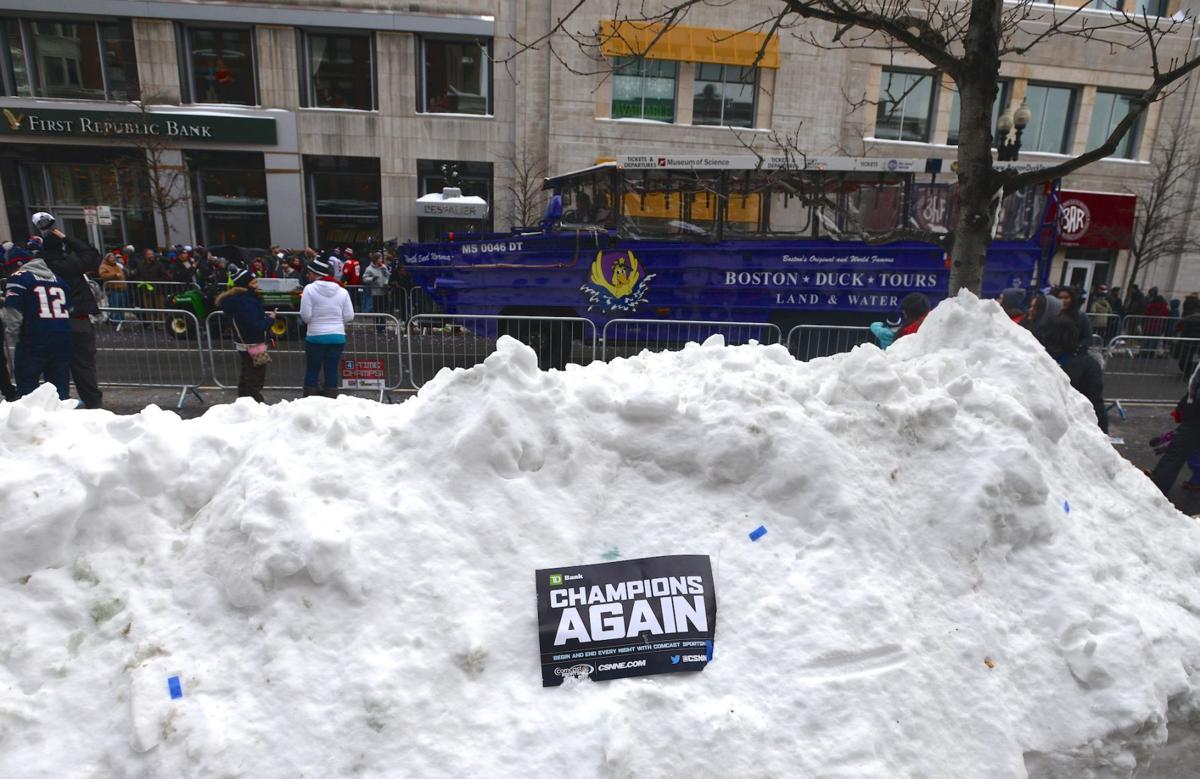 A sign stuck in a massive snowbank along Boylston Street as the tail end of the Patriots celebratory parade heads down Boylston Street.