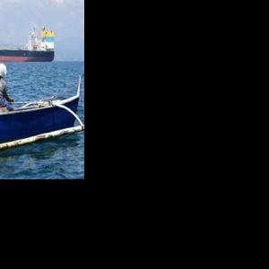 A fisherman travels past the Sara Sky, which last week arrived in the Philippines bearing crude oil from Russia