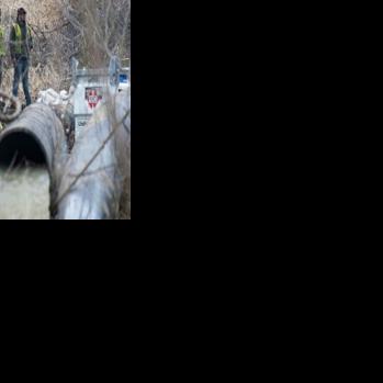Emergency workers look on as raw sewage flows out of a drainage pipe into the C&O Canal near Cabin John, Maryland, after more than 200 million gallons of wastewater spilled into the Potomac River