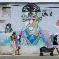 People on their way to the beach walk past a mural of Puerto Rican singer Bad Bunny in Vega Baja, Puerto Rico, the municipality where the global superstar grew up
