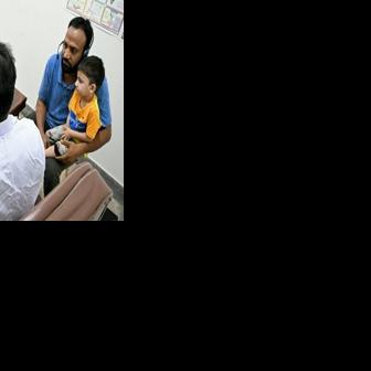 Muhammad Adil (with child) receiving an online and free doctor consultation for his son at a clinic of digital health firm Sehat Kahani in Karachi