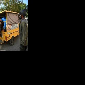 People line up to board an electric tricycle on a street in Havana