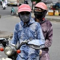 Motorcyclists cover up to avoid the scorching sun in Hanoi