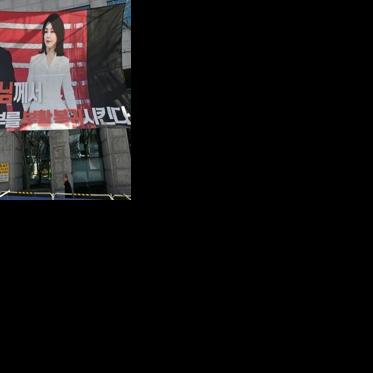 A man walks past a banner showing a picture of South Korea's former impeached president Yoon Suk Yeol and his wife Kim Keon Hee