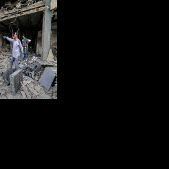 People retrieve equipment from an office building that housed the offices Doha-headquartered news network Al Araby TV following a missile strike in Tehran