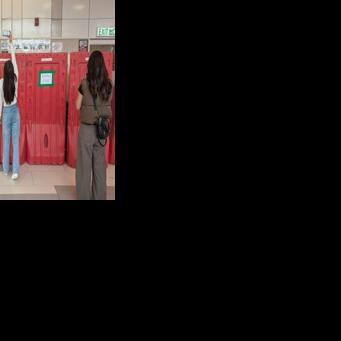 A woman takes a photo with her phone above barricades in front of the student union-run notice board, nicknamed “democracy wall”, at Hong Kong Baptist University