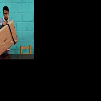 An electoral staffer opens a box containing voting materials before polls open for the presidential runoff election in La Paz on October 19, 2025