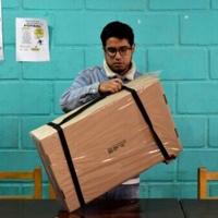 An electoral staffer opens a box containing voting materials before polls open for the presidential runoff election in La Paz on October 19, 2025