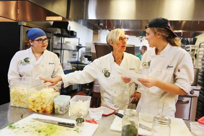 Cathryn Couch (center) helps two young volunteer chefs prepare medically tailored meals for Ceres Community Project, the nonprofit she founded in 2007. Her work inspired a state-funded pilot study.