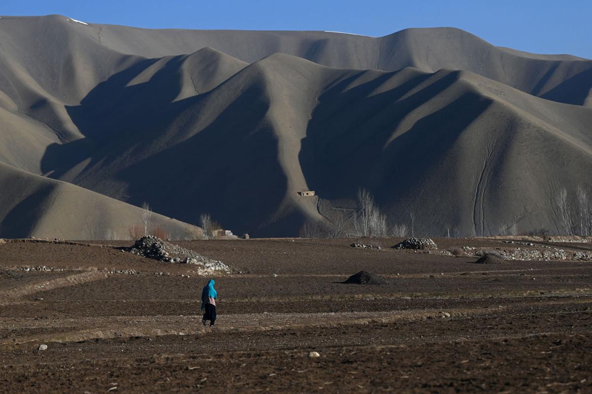 A Hazara woman walks on a land at Dare-Folladi on the outskirts of Bamiyan Province on March 9, 2021.