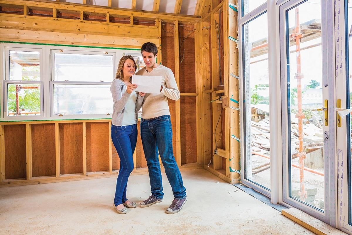 'a man and woman looking at a piece of paper in a room with windows'